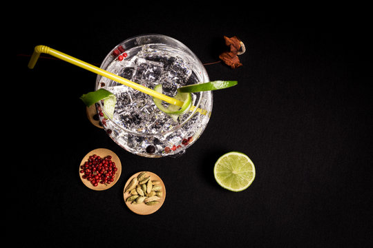 tasty and fresh gin and tonic cocktail on a black background next to your ingredients

