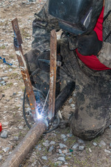 The worker in the welding mask fastens a metal construction by means of electric welding