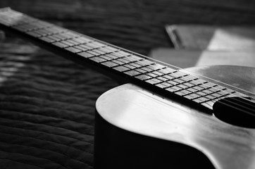 The old guitar and music books illuminated by the sun. Black and white