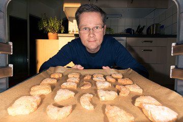 Mann schiebt ein Backblech mit Keksen in den Backofen