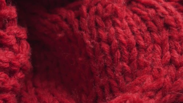 Texture of a red knitted scarf. Closeup shot, slow motion.