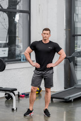 handsome muscular bodybuilder looking at camera in gym
