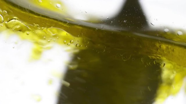 Cucchiaio mescola dell'olio versato in acqua