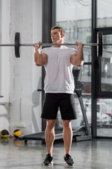 Fototapeta na wymiar handsome muscular bodybuilder training with barbell in gym