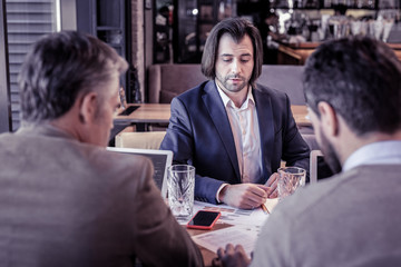 Serious brunette man listening to his colleagues