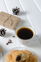 Cup of hot coffee with pastry, new year packs and pine cones