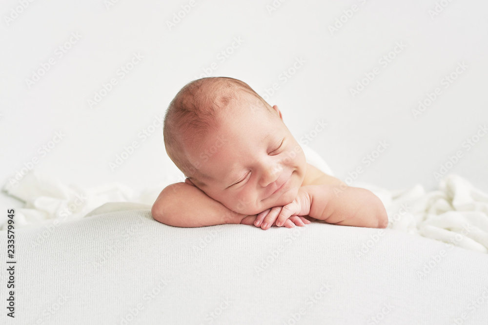 Wall mural cute newborn baby lies swaddled in a white blanket. baby goods packaging template. closeup portrait 