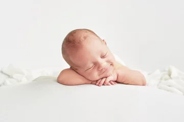 Fotobehang Cute newborn baby lies swaddled in a white blanket. Baby goods packaging template. Closeup portrait of newborn baby with smile on face. Healthy and medical concept.  © Aleksandr