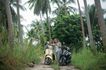 A pair of beautiful women travel by scooter through the jungle in Southeast Asia. Phone navigation