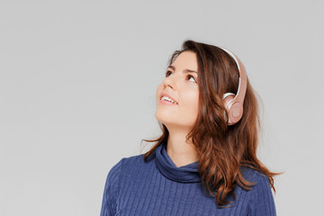 Portrait of beautiful positive girl in headphones enjoying music