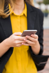 Executive working with a mobile phone in the street with office buildings in the background