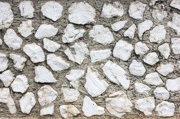 Background with building wall made of white irregular shape natural stones. Old stony textured wallpaper
