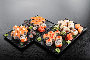 Philadelphia roll with salmon and cucumber. Maki Sushi set on dark pattern background. Sushi Set nigiri, rolls and sashimi served in black square plate. On dark pattern background.