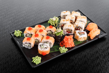 Philadelphia roll with salmon and cucumber. Maki Sushi set on dark pattern background. Sushi Set nigiri, rolls and sashimi served in black square plate. On dark pattern background.