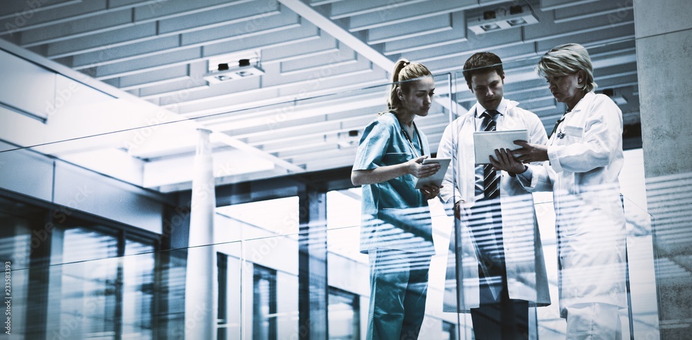 Wall mural medical team discussing over digital tablet in corridor