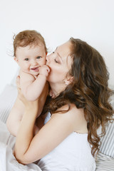 Happy mother hugging her adorable little daughter, greeting card for Mothers Day. Women's Day. March 8. Spring greetings. Happy family at home. Healthy family concept, mom and baby daughter.