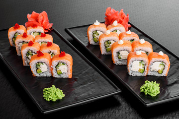 Philadelphia roll with salmon and cucumber. Maki Sushi set on dark pattern background. Sushi Set nigiri, rolls and sashimi served in black square plate. On dark pattern background.