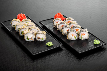 warm roll with salmon. Maki Sushi set on dark pattern background. Sushi Set nigiri, rolls and sashimi served in black square plate. On dark pattern background.