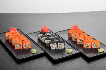 Maki Sushi set on dark pattern background. Sushi Set nigiri, rolls and sashimi served in black square plate. On dark pattern background.
