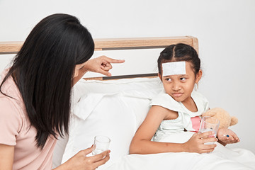 Mother feeding syrup medicine to little girl