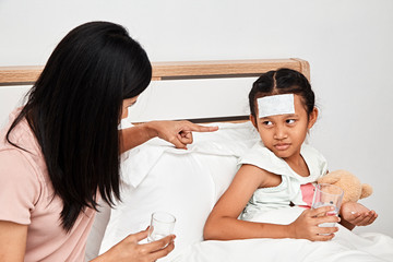 Mother feeding syrup medicine to little girl