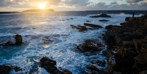 Obraz premium Sunset over Rugged Coastal Landscape