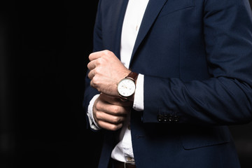 cropped shot of businessman in stylish suit with wrist watch isolated on black