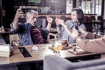 Joyful males shooting video on their gadgets