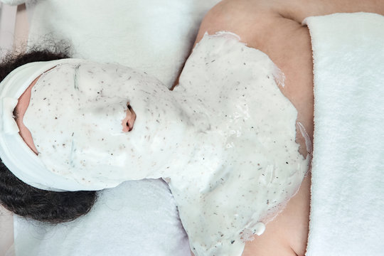 Woman with cosmetic alginate mask on her face. The procedure for skin care in the beauty salon. Top view
