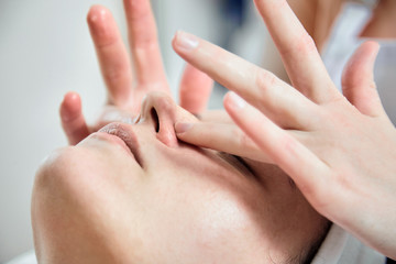 Face massage. Fingers of masseur. Nose and hands closeup. Facial skin care. Woman at beauty spa salon.