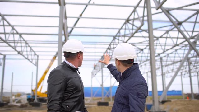 male engineers construction supervisors in hard hats working and discussing plan. They checking quality of object on construction site. Businessman engineer architects builders architect man 4 K