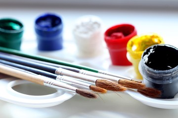 Colored paints with brushes on a white palette