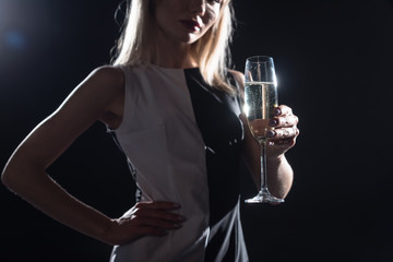 cropped shot of young woman holding glass of champagne on black