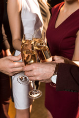 cropped shot of friends clinking champagne glasses during holiday party