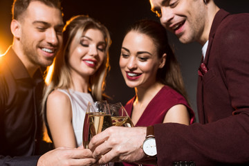 group of friends clinking champagne glasses during party on black