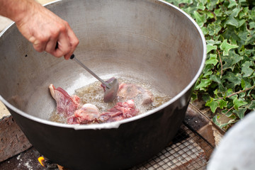 Cook mixes lamb pieces in cauldron