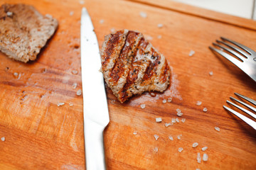 Grilled beef on wooden plate with knife