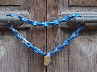 Closed door with chain and padlock. The chain has the shape of a heart.