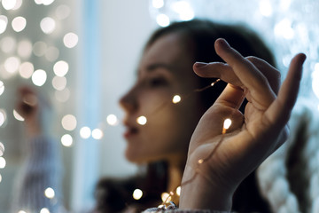 Closeup of woman's hands holding Christmas lights, shallow selective focus