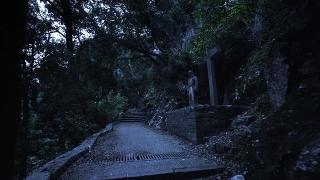 Night dark mystical stairway road in a mountain park with ancient christian statues . Fantasy dangerous twilight way. Dolly shot