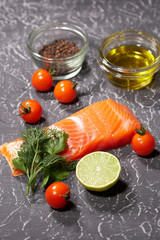 A piece of salmon on a gray background, tomatoes, dill, olive oil, lemon. Selective focus