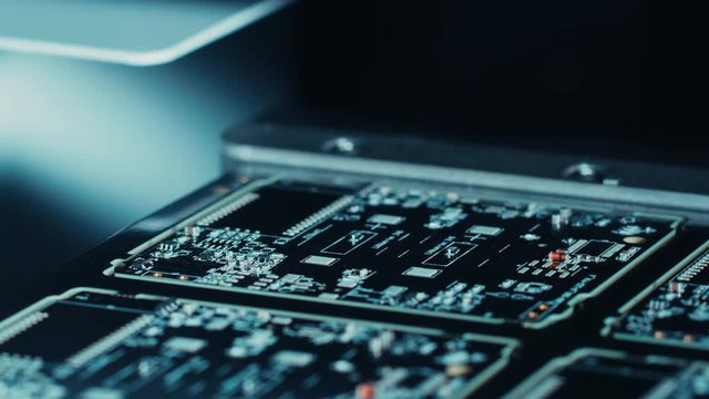Close-up Macro Shot of Electronic Printed Circuit Board Being Assembled with Automated Robotic Arm, Surface Mounted Technology Connecting Microchips, Transistors, Capacitors to the Motherboard.