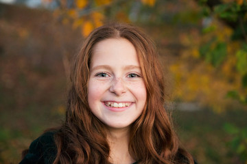 Red-hair girl dancing and playing in the autumn garden full of colorful leaves.