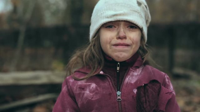 Frozen poor homeless girl holding cardboard house and looking at camera. Focus on the house and then on the face.