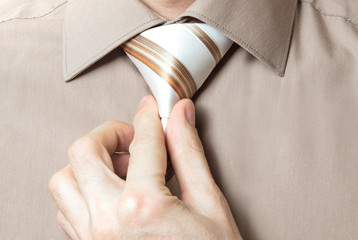 Businessman straightens his tie closeup on white background