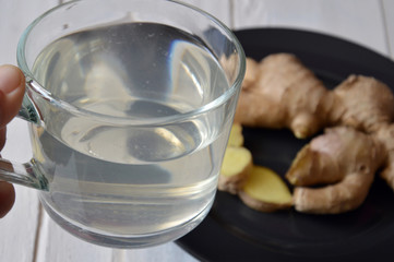 sliced ginger on black plate and a cup of ginger tea