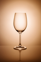 Empty wine glass isolated on the light background toned orange.