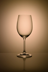 Empty wine glass isolated on the light background toned orange.