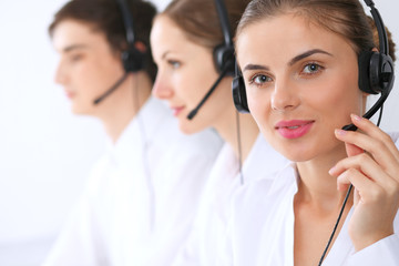 Call center operators at work. Focus at beautiful business woman in headset