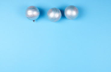 Three Christmas baubles on blue background.